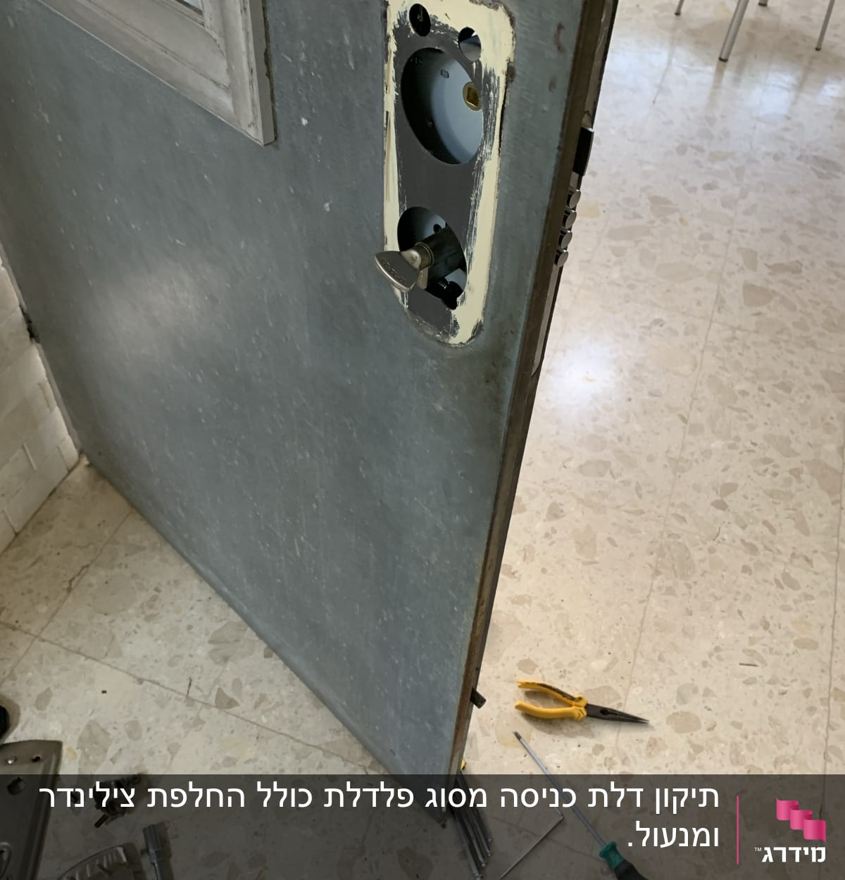 דלת פתוחה עם חור למנעול, מברג ופלייר על הרצפה